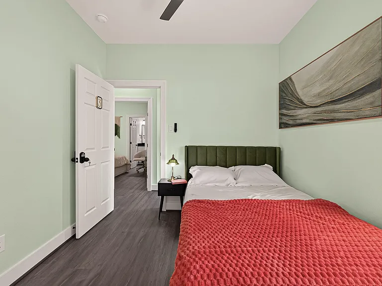 Furnished private bedroom with a full-size bed, nightstand lighting, and easy access to the hallway.
