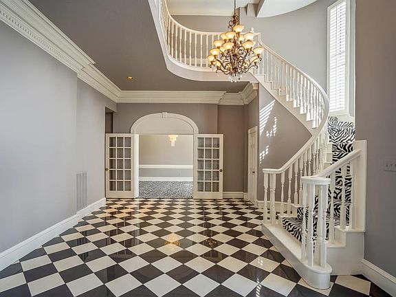The entry to this home has a tremendous WOW factor! The 2 foyer has a family of chandeliers, spiral staircase, stunning crown molding & wood work throughout.