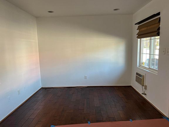 living room with recess lighting, in wall air conditioner unit, double panel window, hardwood floor and shutter