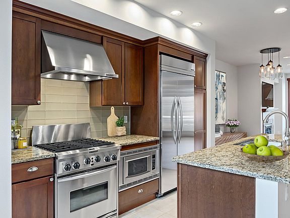Gourmet kitchen with slab granite counters, glass tile backsplash, gas oven/range, and built-in refrigerator. Kitchen Aide appliance package. (second floor)