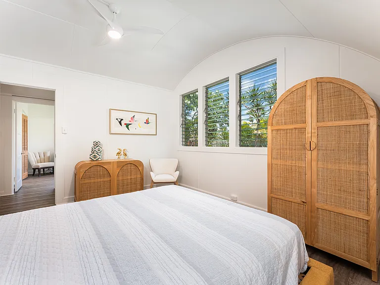 Bedroom 2 featuring vaulted ceilings, luxury vinyl flooring, and windows overlooking the landscaped backyard.