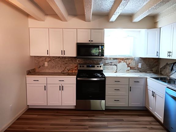 Lovely open kitchen, dining room, living room area with vigas, window and lovely countertops.