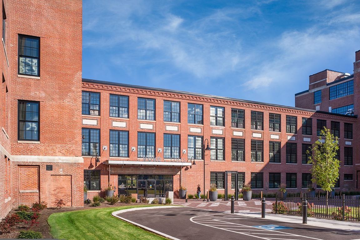 Voke Lofts apartment community exterior featuring modern brick architecture and landscaped courtyard