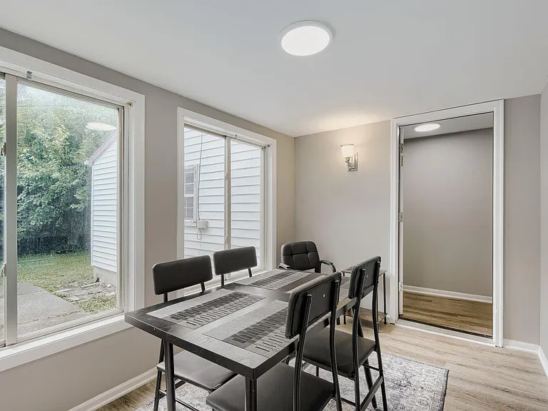Dining area near the entry with a table setup and large windows offering yard views and plenty of natural light.