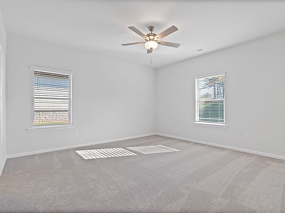 Large Primary bedroom with Ceiling fan located at the back of home.