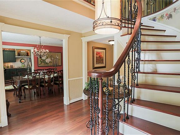 Entry with curved staircase and fabulous lighting flows into the dining and kitchen areas. Notice th