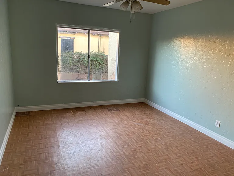 Bedroom 2 with large window providing natural light and center ceiling fan with light fixture.