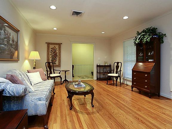 A formal living room features hardwood floors, recess lights, and wood blinds.