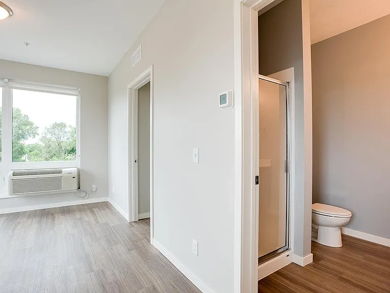 ge windows and wood-style flooring create a bright, inviting space, with a bathroom just off the main living area for added convenience.