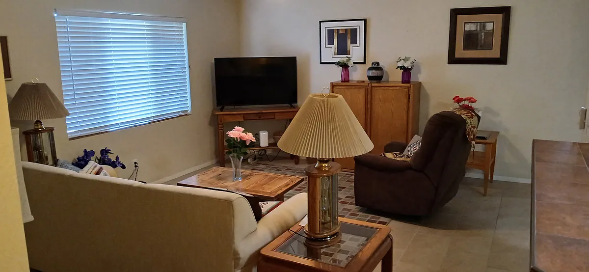 The cozy living room features a comfortable couch, a soft recliner, and a smart TV. - 132 E Los Arcos