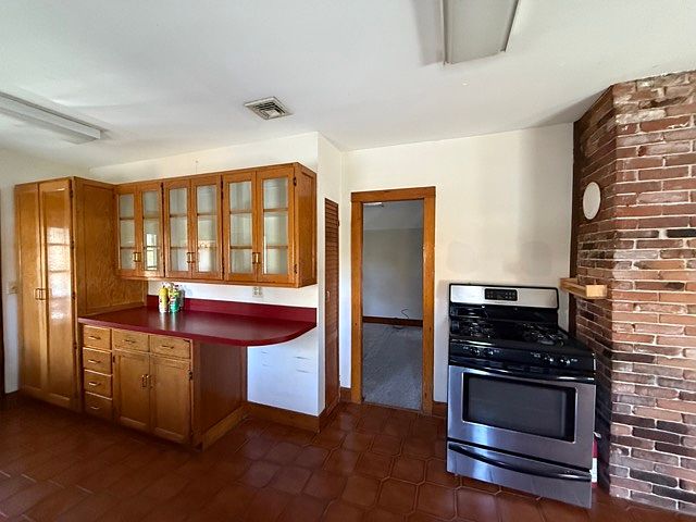 Kitchen with glass front upper cabinets, pantry storage, gas range