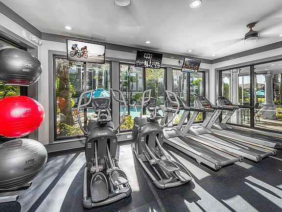 Image of the 24-hour full body fitness center with cardio equipment and a view of the pool.