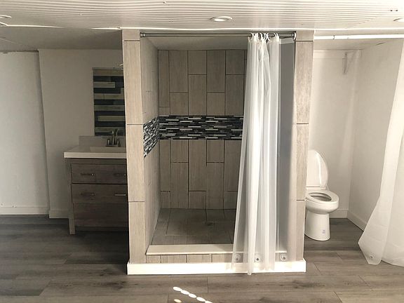 To the side of the A/C,you_re looking at the new toilet bowl and expanded shower.To the left of shower is the_bathroom_s_wash basin/vanity.