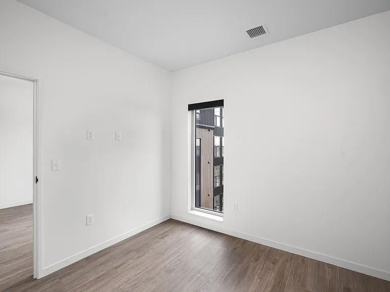Bright and airy room with sleek wooden floors and a large window offering urban views. Bright and airy room with sleek wooden floors and a large window offering urban views.