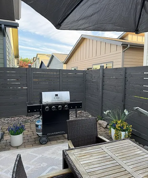 The outdoor patio is perfect for entertaining, featuring a large dining table with umbrella shade and a gas grill for easy outdoor cooking and dining.