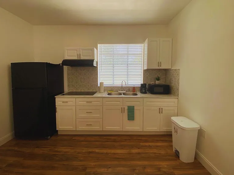 Fully equipped kitchen with stove, range hood, refrigerator, microwave, and coffee maker.