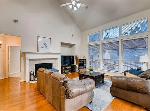 Family room with hardwood floors, high ceiling, fireplace and view of back yard and deck.