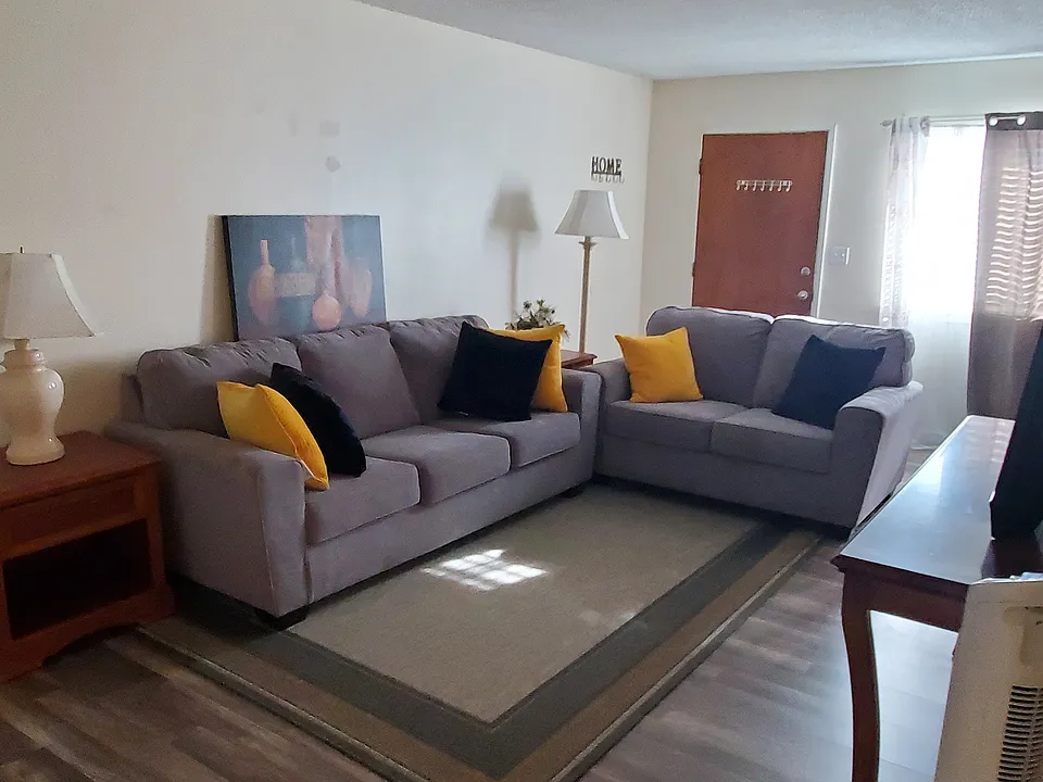 Spacious living room with new Ashley sofa & loveseat, large TV.