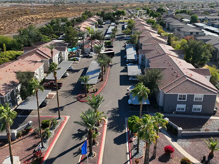 Experience desert living at its finest! This aerial view of Sedona Peaks highlights the beautiful community layout, complete with lush palm trees and breathtaking mountain views.