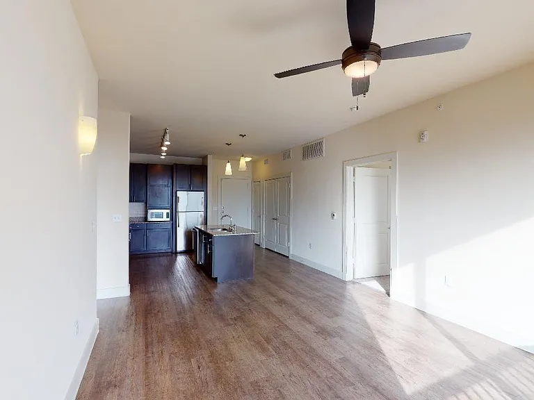 Apartment kitchen with stainless steel appliances in select homes, dining and living room with wood-style flooring.