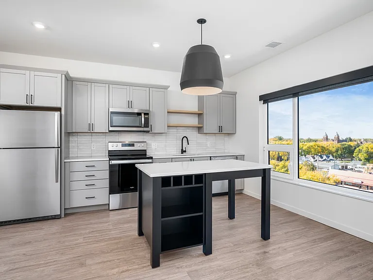 Modern kitchen with sleek gray cabinets, stainless steel appliances, and a spacious island, featuring large window with scenic views. Modern kitchen with sleek gray cabinets, stainless steel appliances, and a spacious island, featuring large window with s