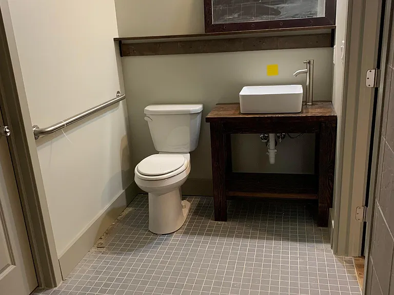 Bathroom with farmhouse vanity and vessel sink. Full length shelf holds mirror and toiletries