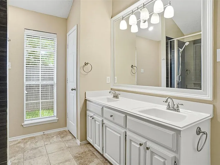 Bathroom featuring a double vanity with white cabinetry, integrated sinks, and chrome faucets