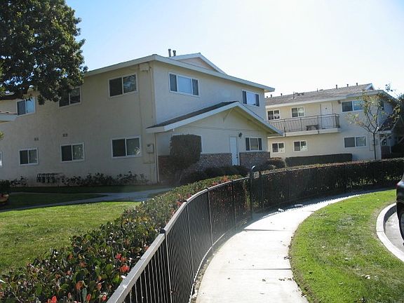 Green grass around apartment, sidewalk, and street parking.