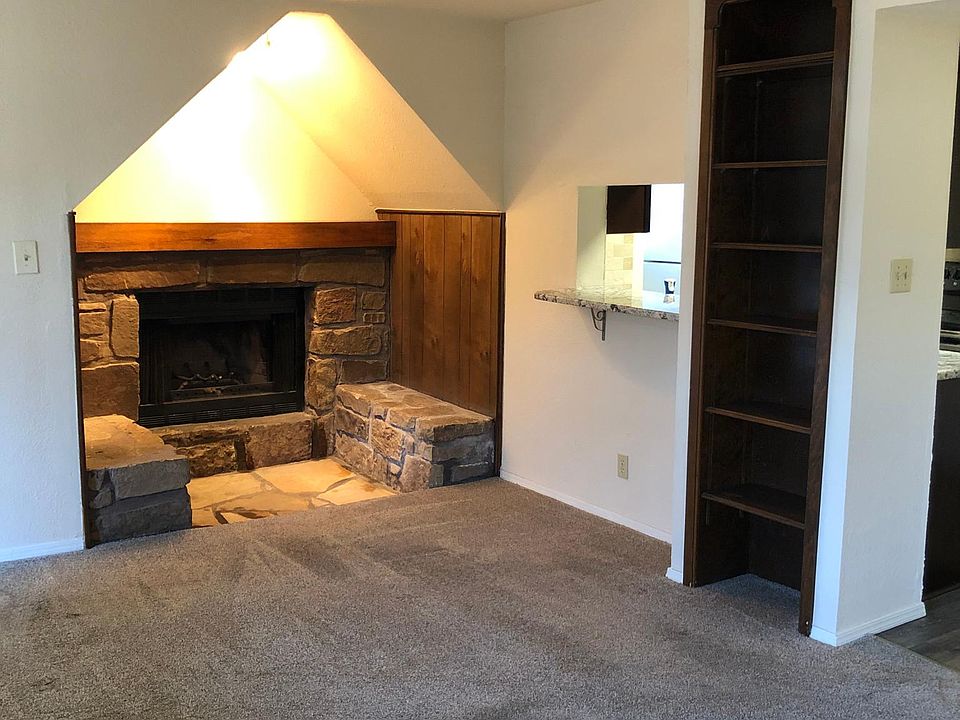 Living room with fireplace nook, built-in shelves, and look through into kitchen