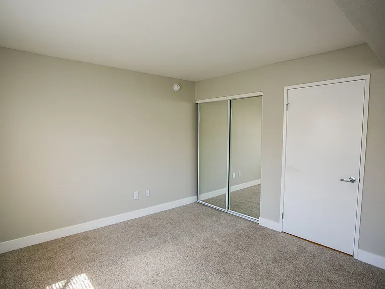 Bedroom with large baseboards, two-tone paint, and mirrored sliding closet doors.