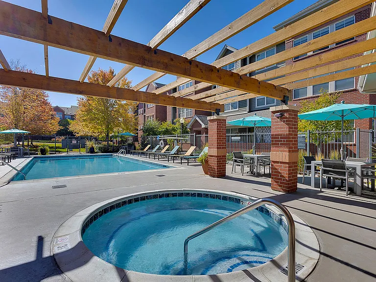 Charming outdoor space featuring a sparkling swimming pool, cozy hot tub, and inviting patio seating with umbrella shades.