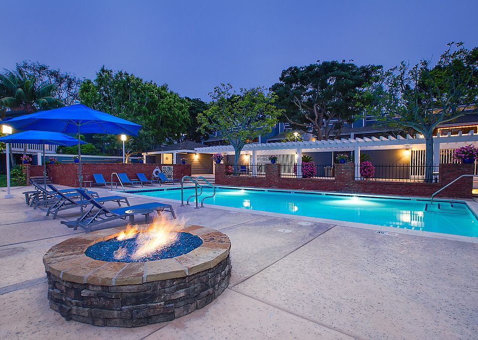 Swimming pool surrounded by lounge chairs and a fireplace.