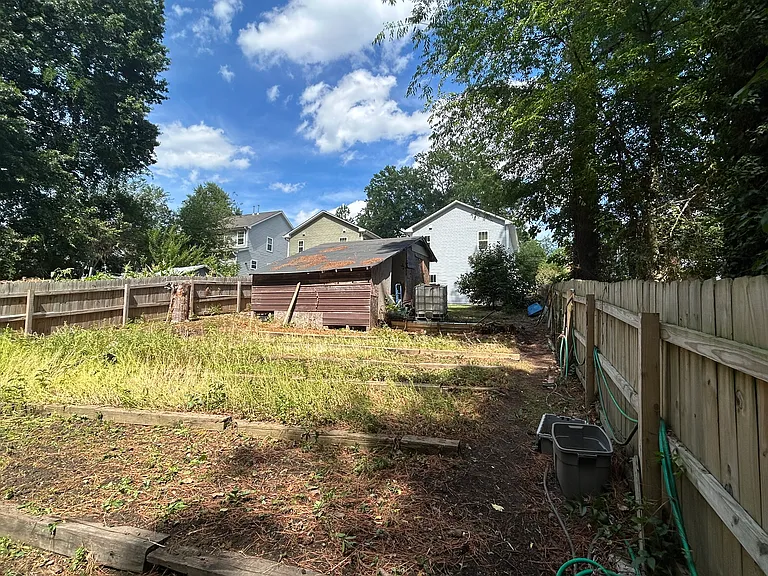 Another view of the second half of the backyard. A hose is secured along the length of the wooden fencing, which is convenient for watering and easily reaching every corner of the garden.