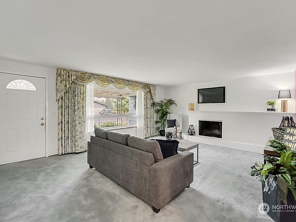 The entry opens into the luminous living room, complete with a hearth, mantle & cozy wood-burning fireplace. >