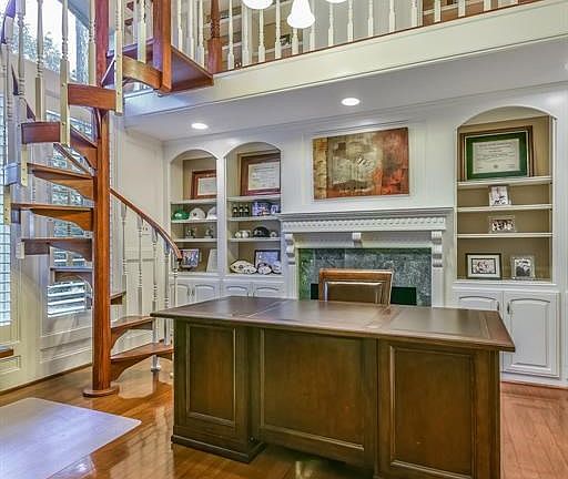 Handsome two-story study/library is highlighted by a fireplace with decorative surround as well as the spiral staircase leading to additional storage above.
