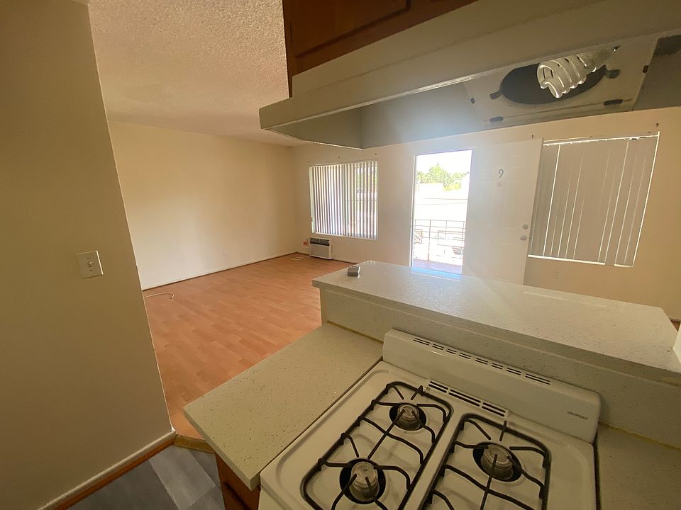 View of living room on right with A/C unit below window and dining area on left.