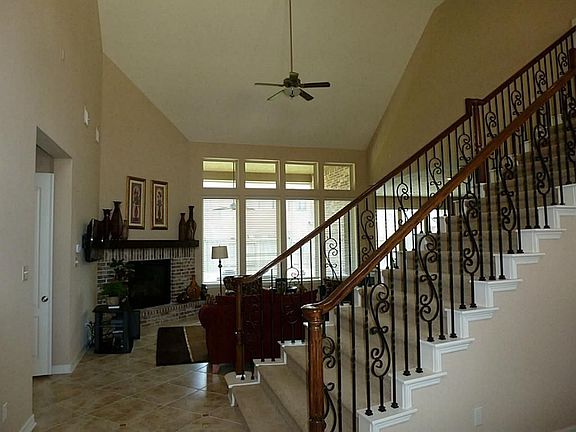 Enter to a view of the family room with corner fireplace, soaring ceilings & wall of windows overlooking the back yard.