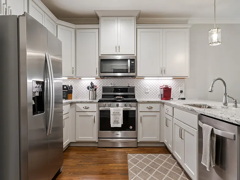 The well-appointed kitchen features stainless steel appliances, stone counter tops, and classic shaker cabinetry.