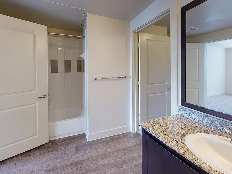 Apartment bathroom with large soaking tub and wood-style flooring.