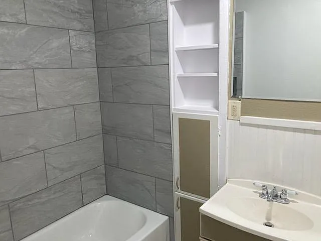 Master bathroom again with mirror, sink, and storage. Toilet is to the right by a window.