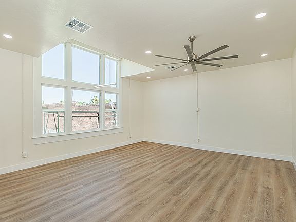 Large High Vaulted Ceiling with Custom Fan, Amazing Large Windows, Luxury Vinyl Plank Flooring, And Automatic Roll Down Shades.