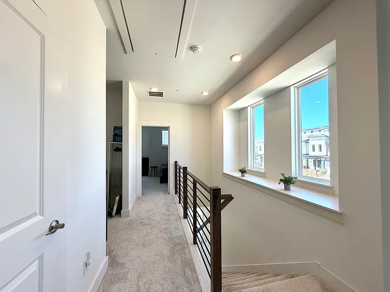 The hallway connecting the primary suite and second bedroom is beautifully designed, with a window that enhances natural light and openness.