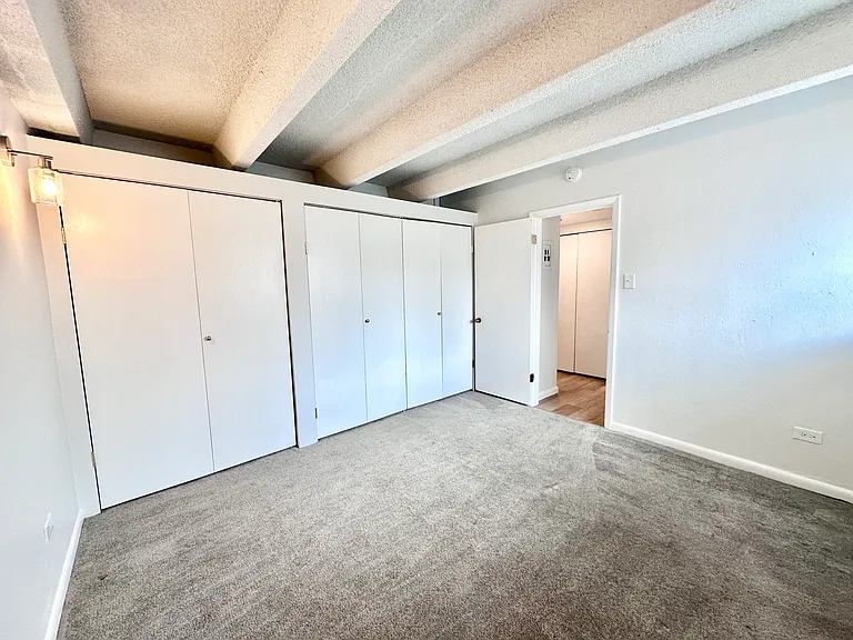 Bright and spacious bedroom with modern white closets and plush carpeting, offering a serene living space. Bright and spacious bedroom with modern white closets and plush carpeting, offering a serene living space.