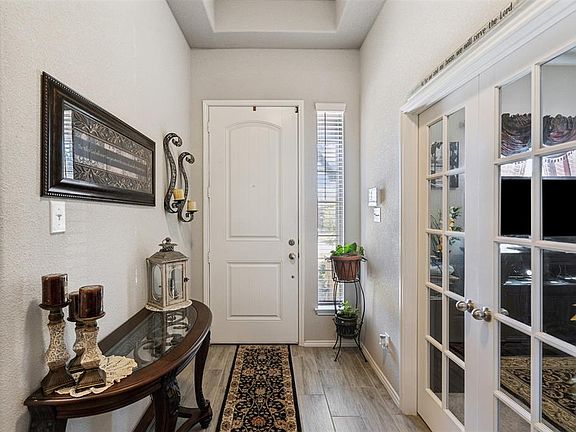 Bright open entryway with tray ceilings. French doors open to the office.