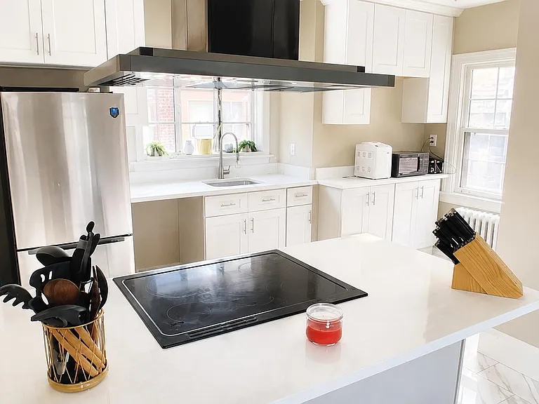Updated kitchen with ample white cabinetry, generous counter space, and an island cooktop with vent hood for easy meal prep.