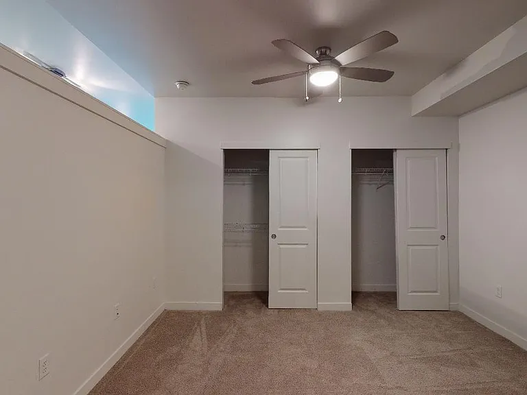 Spacious apartment bedroom with plush carpet flooring.
