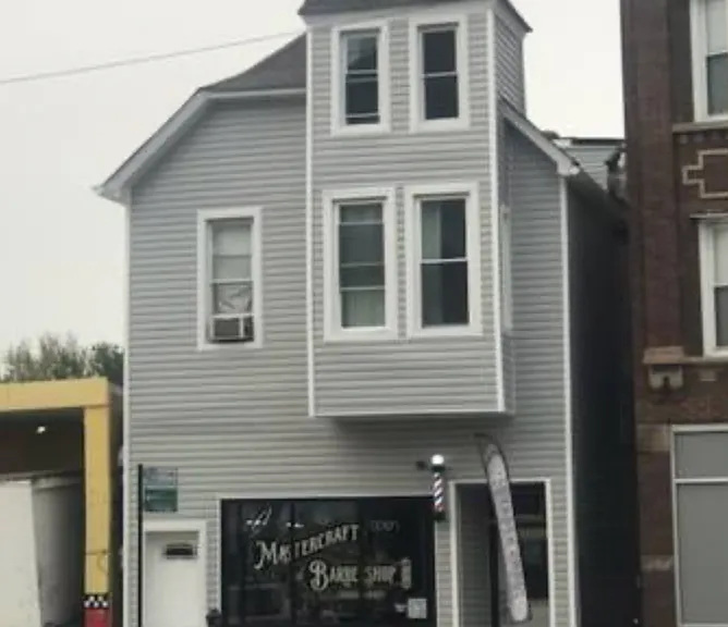Front features a commercial unit, barbershop. The private gated entrance for all 6 units is located to the left side of the home in between the property and the brick building next to it.