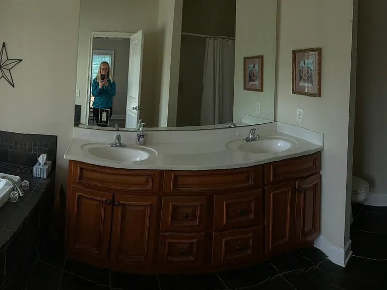 Tub, shower to the right, double sink and toilet in a tiled bath