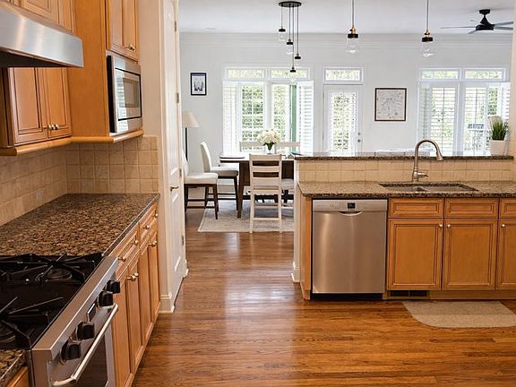 Open kitchen with granite countertops, professional-style gas range, and ample cabinetry.