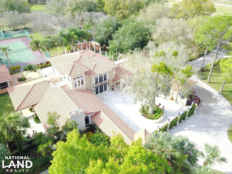 Home with tree-lined driveway, pool, and tennis court